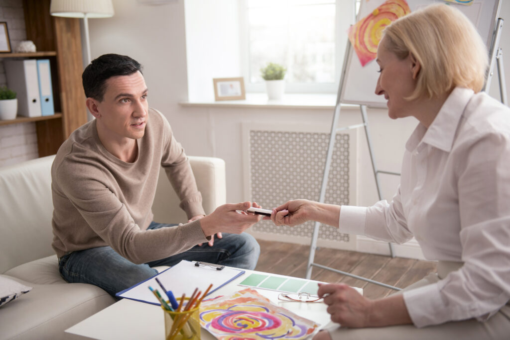 Creative method. Earnest attractive man visiting psychologist while taking marker