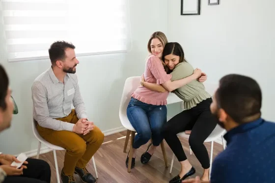psicoterapia sistemica en retiro grupo de personas y dos mujeres abrazadas